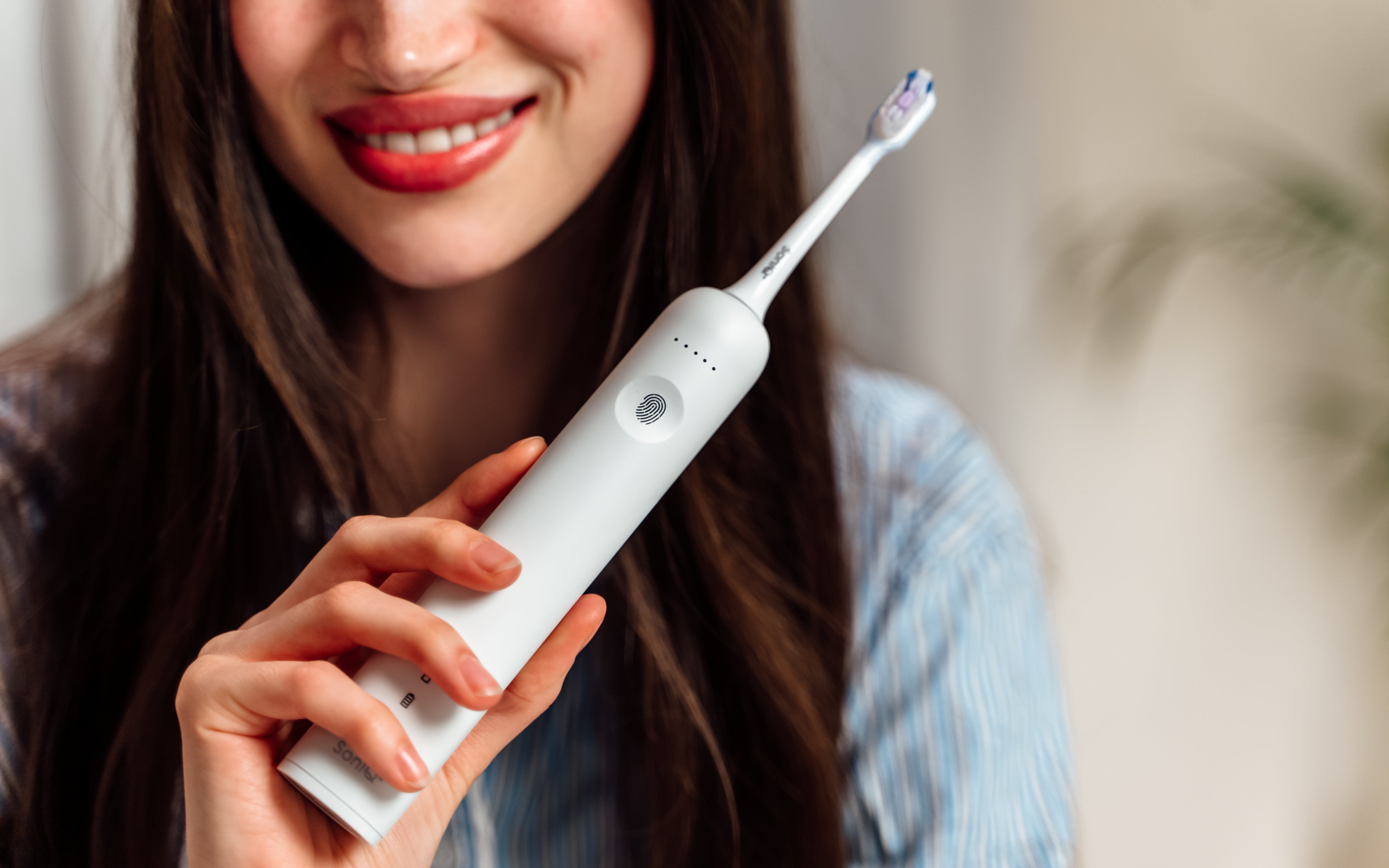 ZENT® SoniQ™ – Aktywna szczoteczka soniczna z ruchem oscylacyjnym 40° trzymana przez uśmiechniętą kobietę