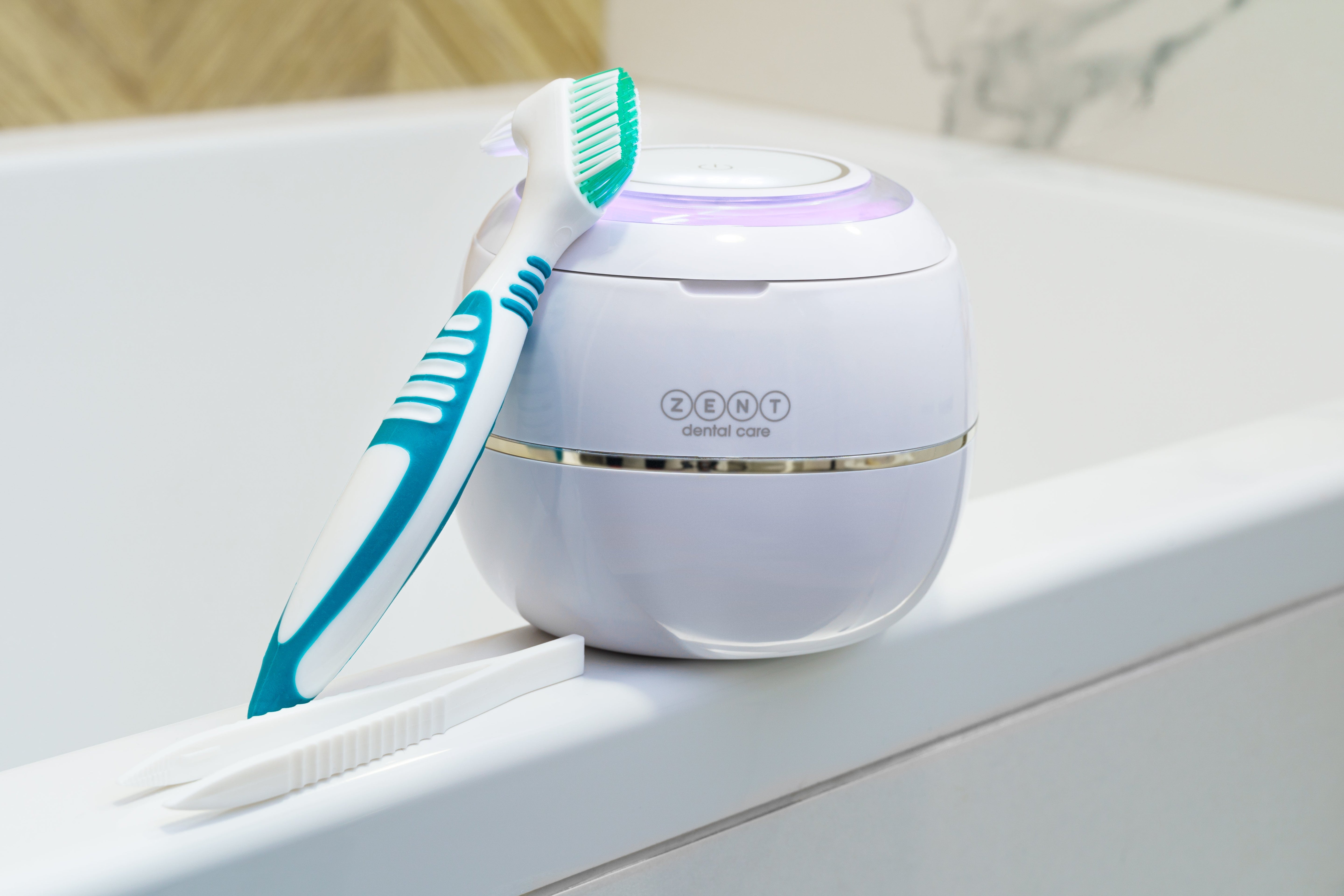 Na wannie leży myjka ultradźwiękowa ZENT® Ultrasonic Cleaner, o którą opiera się szczoteczka